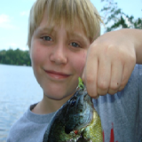 A boy holding a fish in his hand.