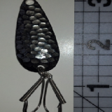 A black and silver fish hook with a scale in the background.