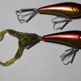 Two metal fishing lures with a green string attached to them.