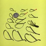 A group of fishing hooks and a penny for size.