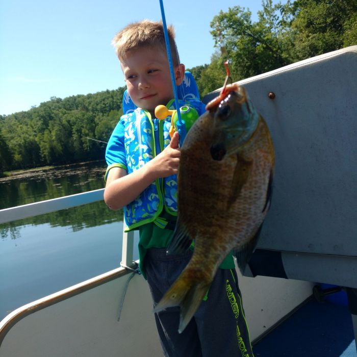 A boy holding onto a fish while fishing.